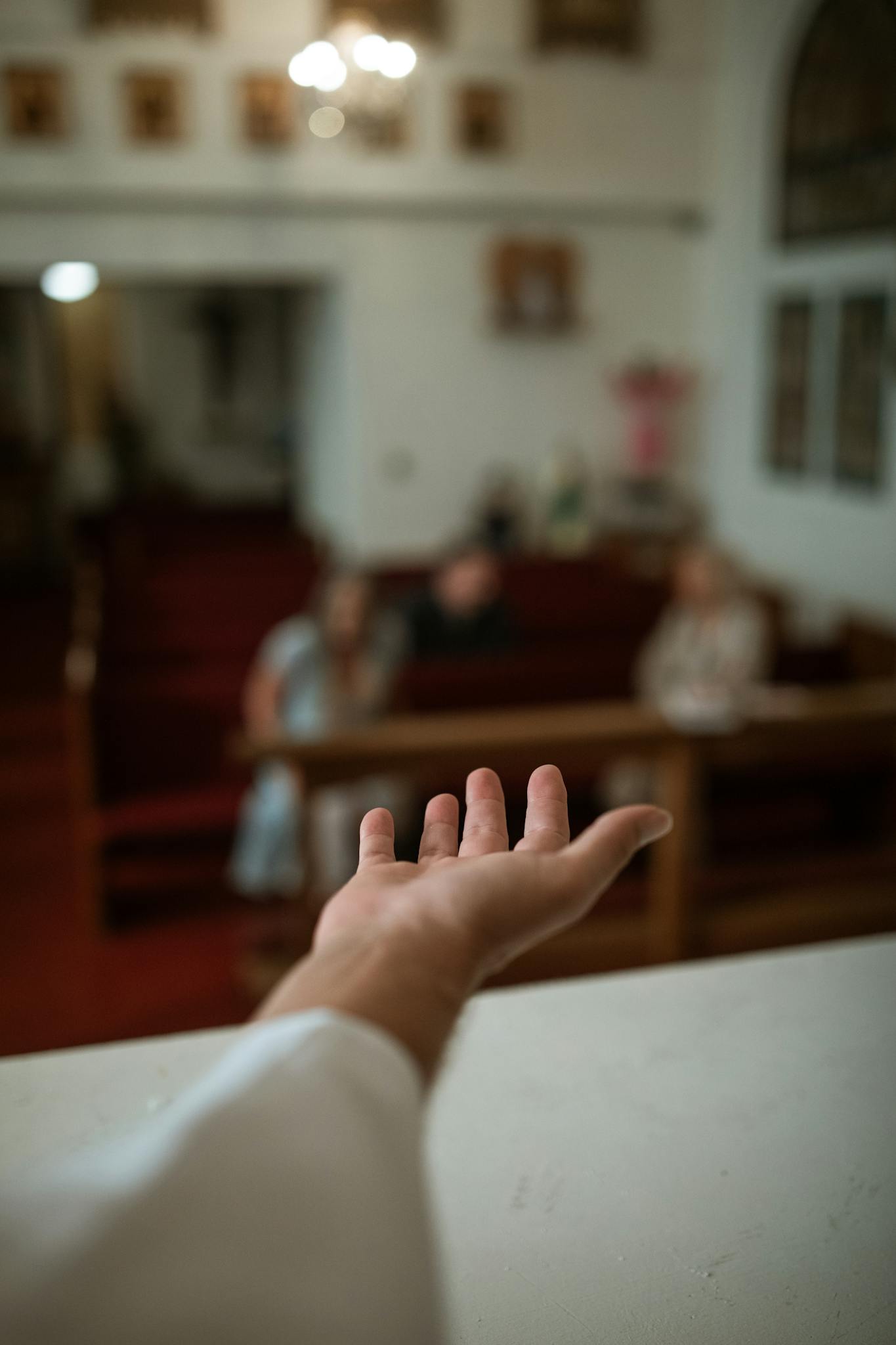 A hand reaching out in a church setting, symbolizing faith and community.