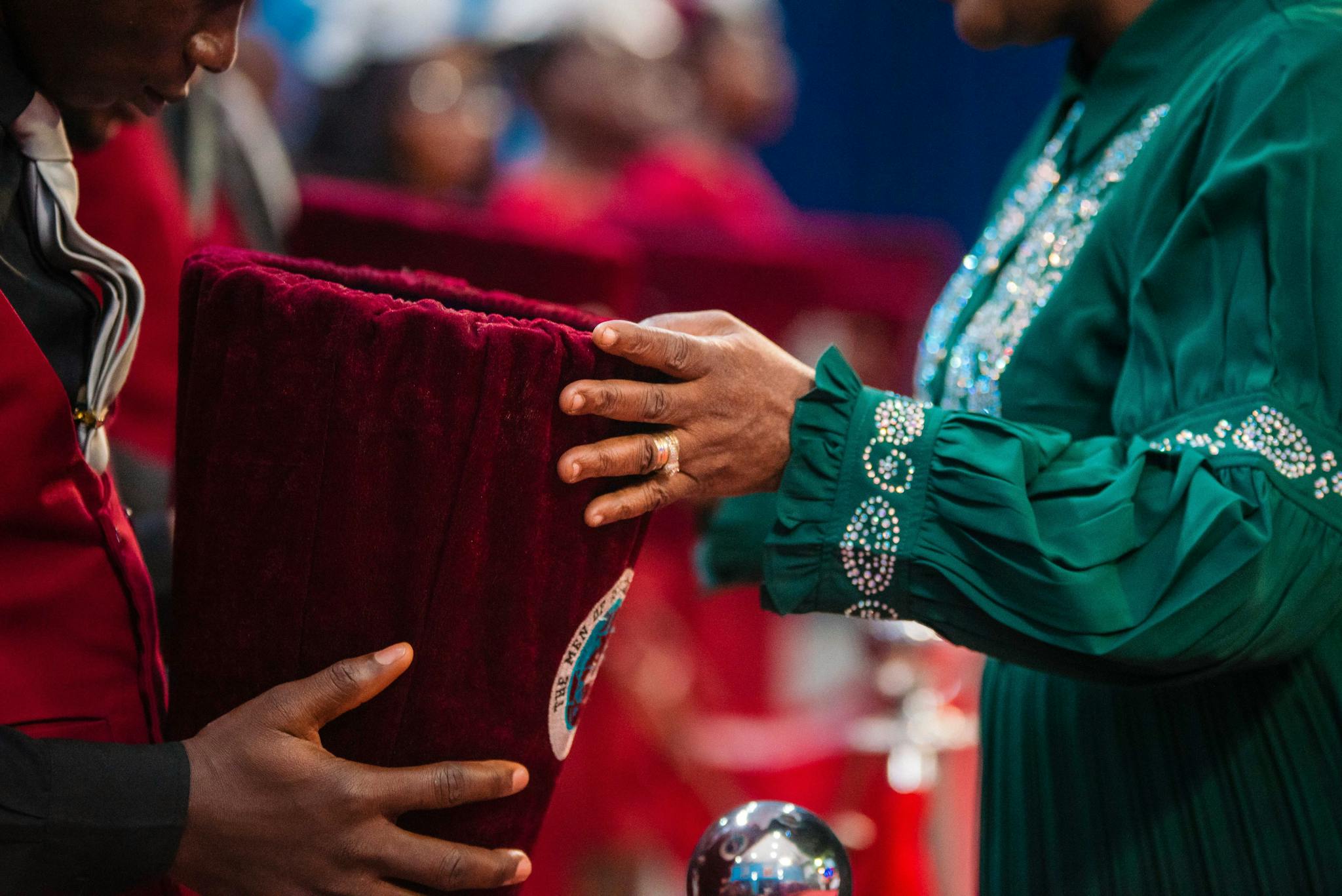 Two individuals participate in a church offering ceremony, showcasing devotion and faith.